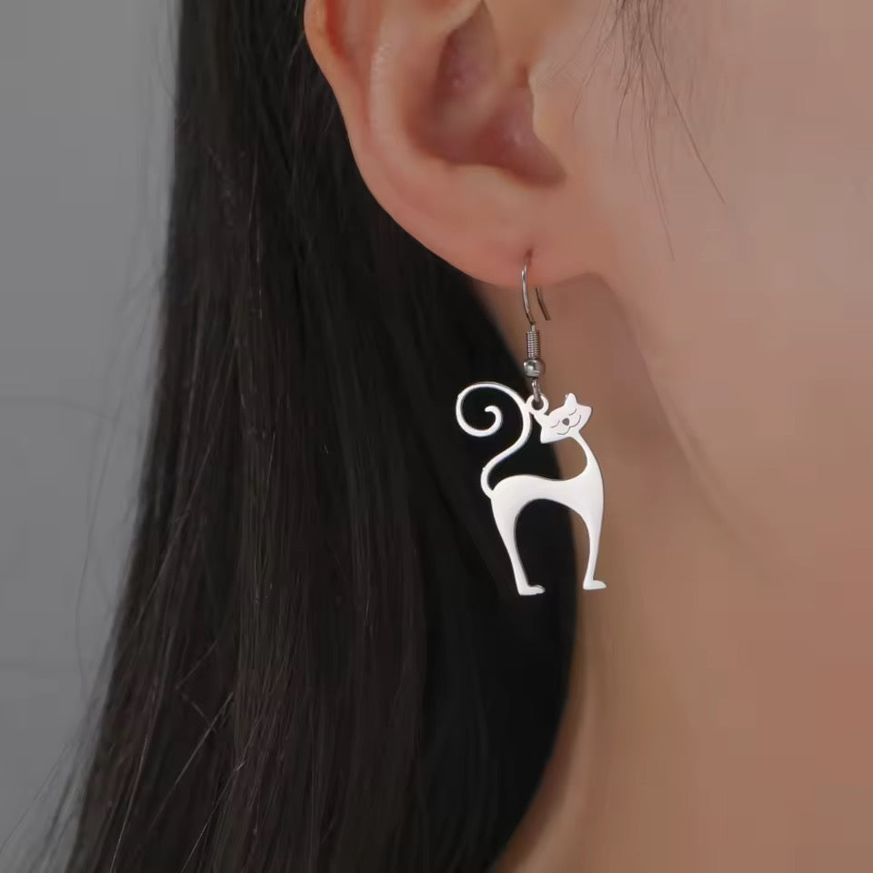 Triple T Studios silver Atomic Cat earrings worn by a person with dark hair