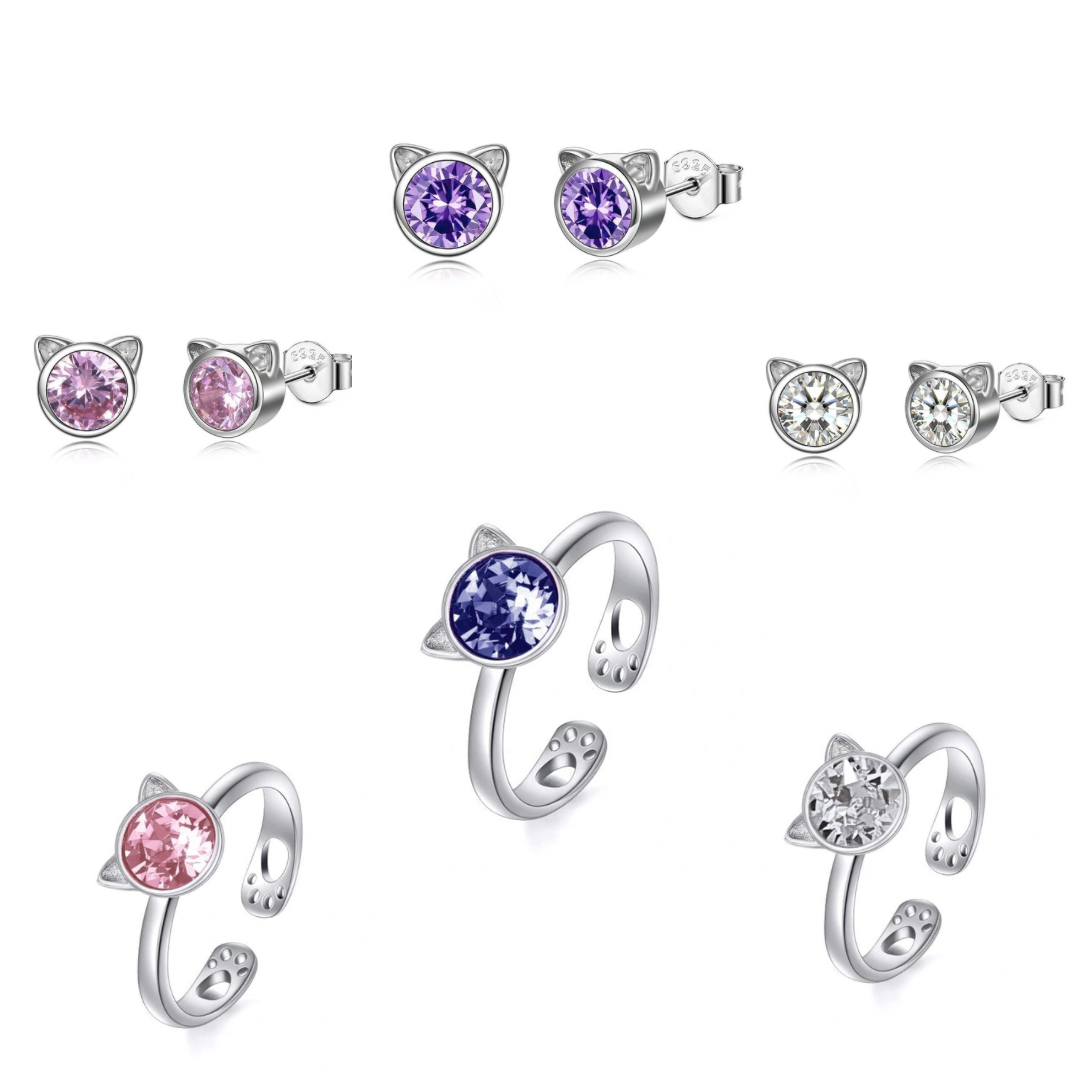 Set of cat-shaped earrings with colored gemstones on a white background