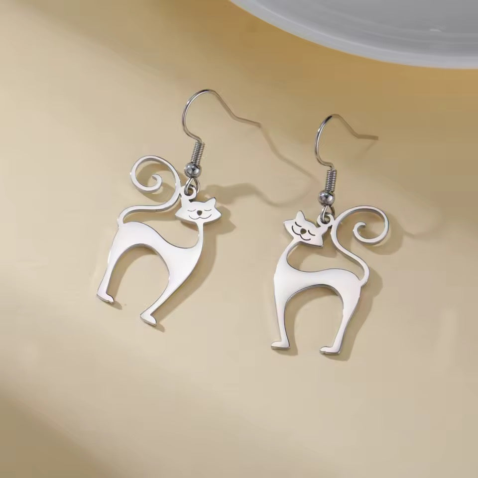 Sophisticated Silver atomic cat-shaped earrings hanging from silver ear wires on a beige background
