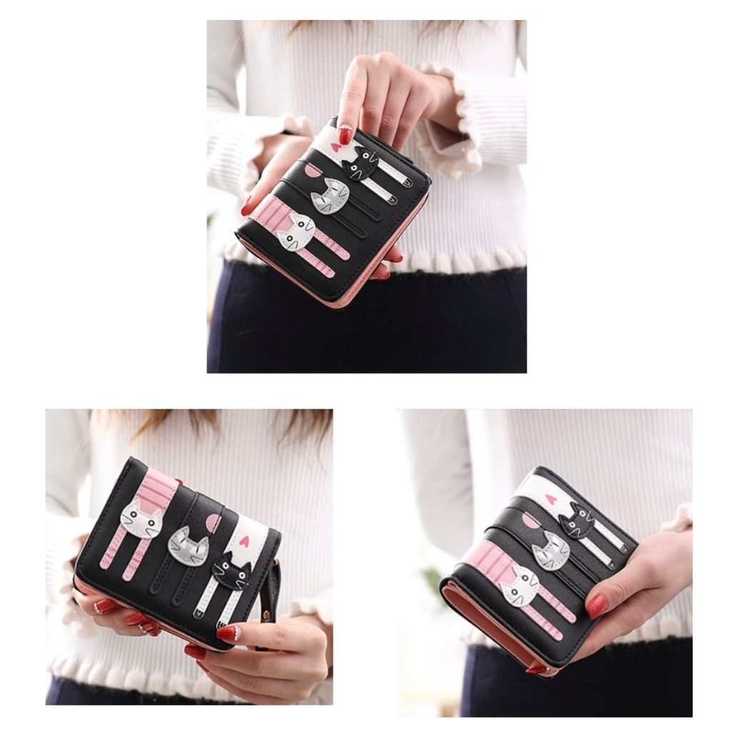 Black wallet with pink and white cat design held by a person wearing a white sweater.