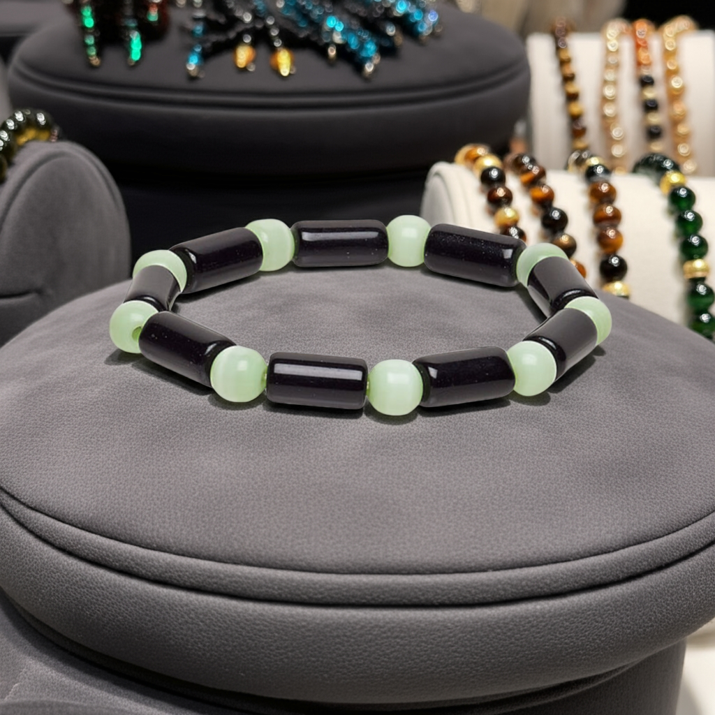 black and green beaded bracelet sitting on black leather cushion