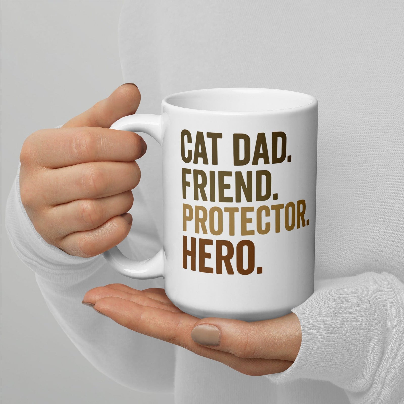 person holding white mug that says cat dad, friend, protector, hero