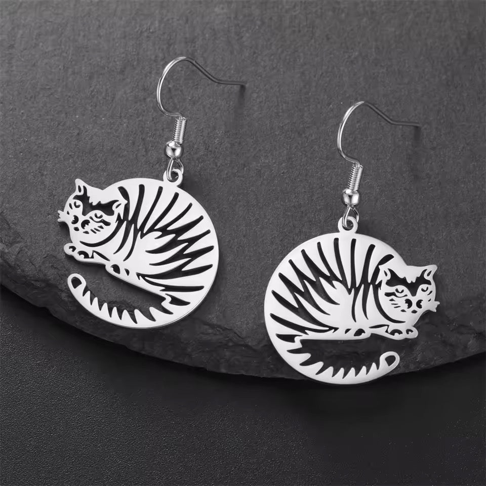 Silver cat-shaped earrings on a dark stone surface