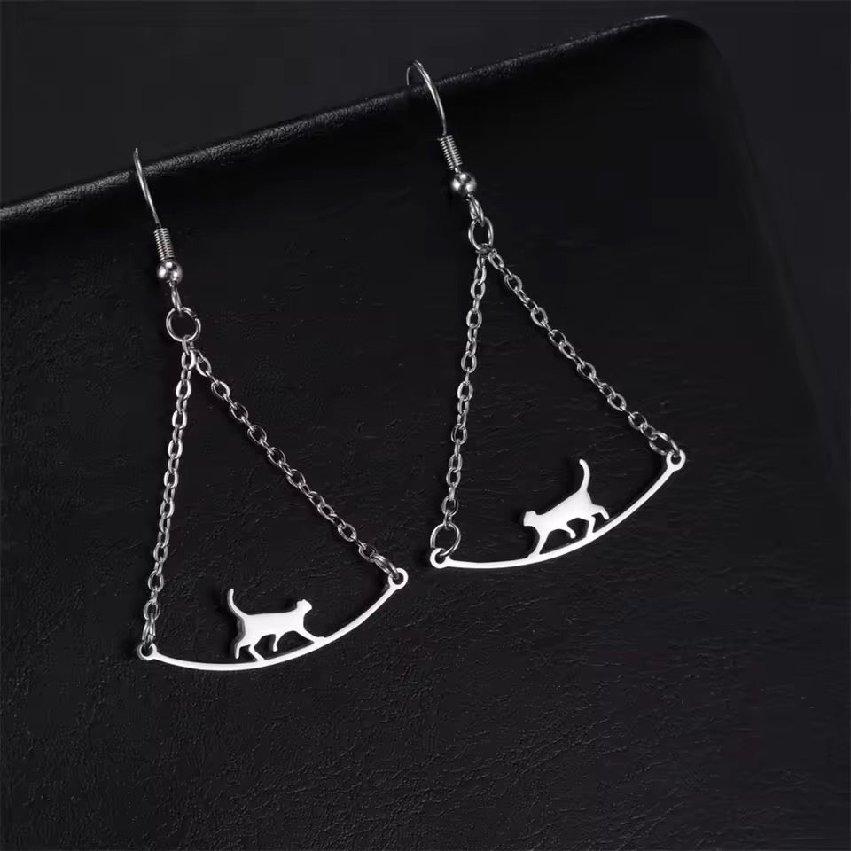 Silver cat-shaped earrings on a dark background