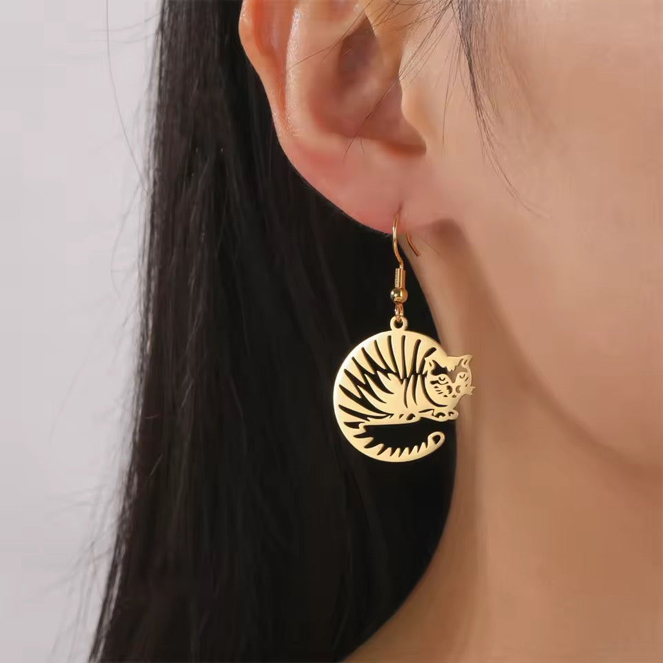 Gold earring with tiger design worn by a person against a neutral background