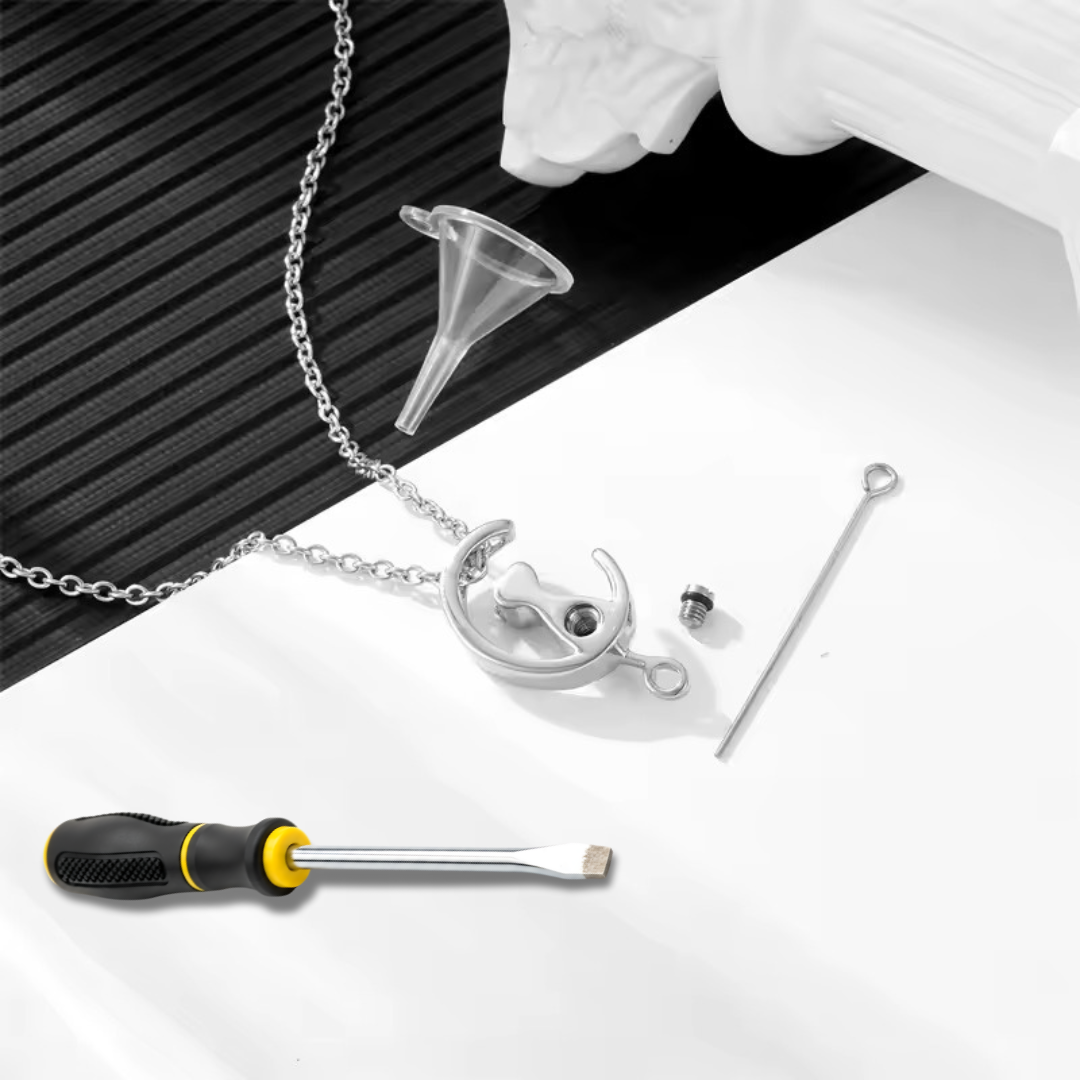 A pendant with a silver cat sitting on a crescent moon dangles from a silver necklace. The pendant is a keepsake memorial that holds favorite pet’s ashes.