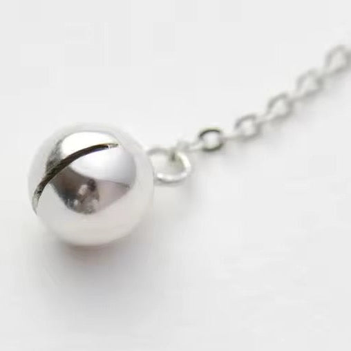 Silver cat inspired necklace with a spherical bell pendant on a white background