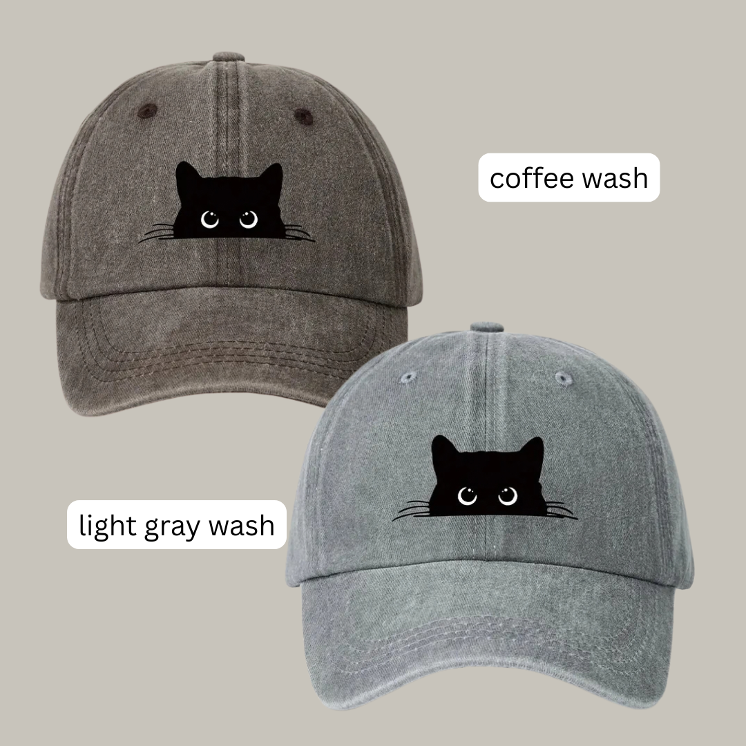 Two baseball caps shown on a plain beige background, labeled 'coffee wash' and 'light gray wash.' Each cap has a black cat face graphic on the front.