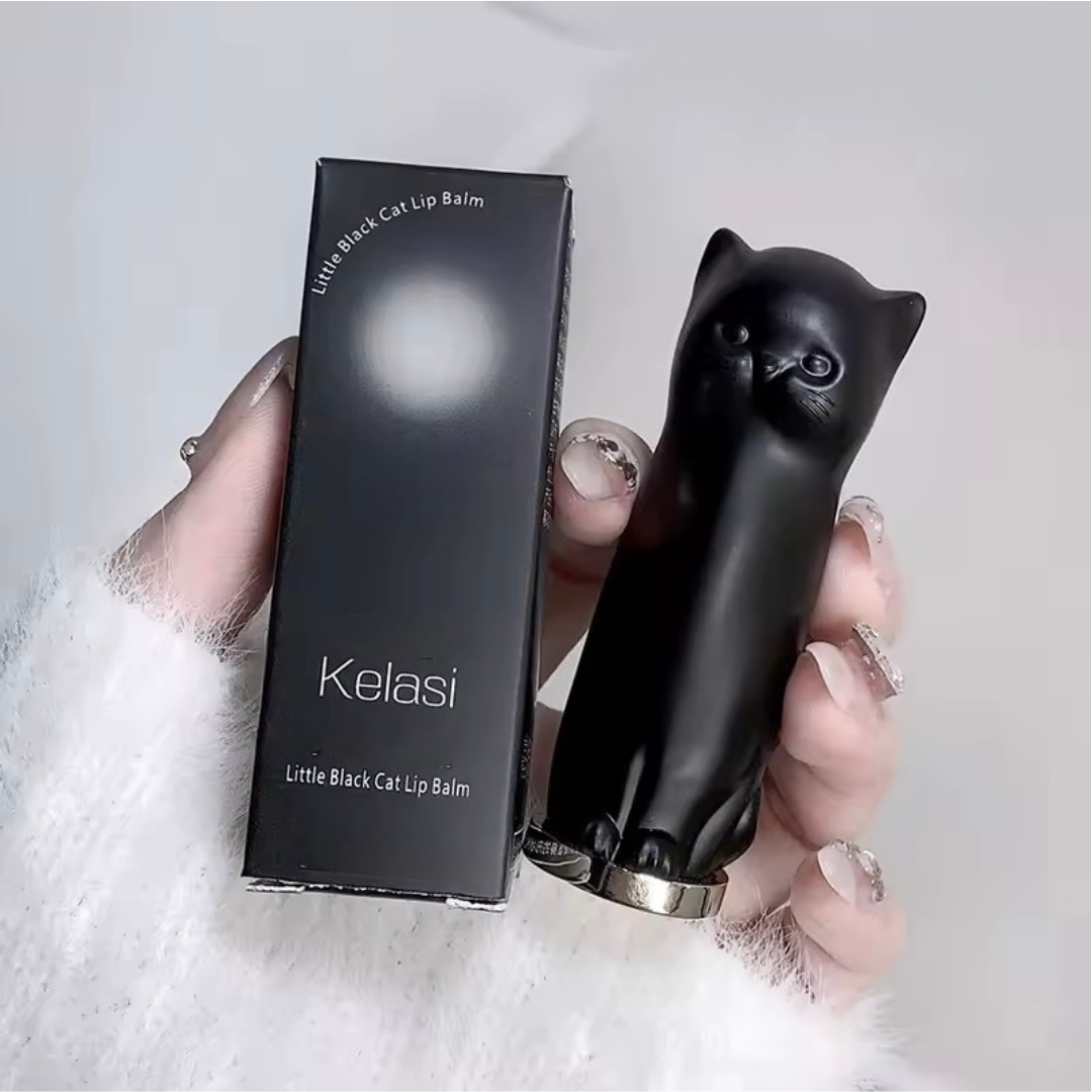 Black cat-shaped lip balm and packaging held by a hand on a light gray background
