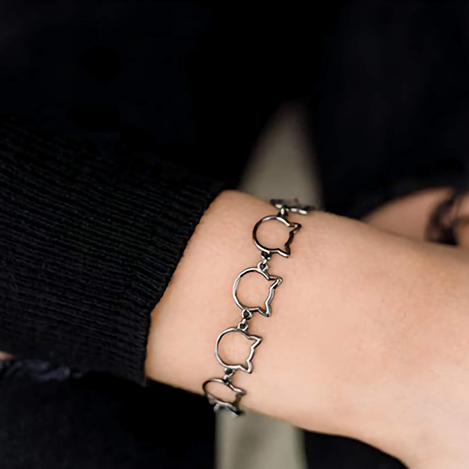 Bracelet with cat links worn on a wrist against a dark background