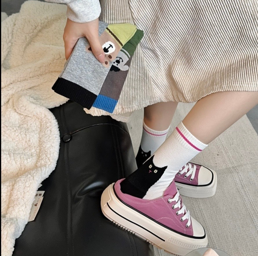 Person wearing colorful socks and pink sneakers with a striped skirt and beige sweater.
