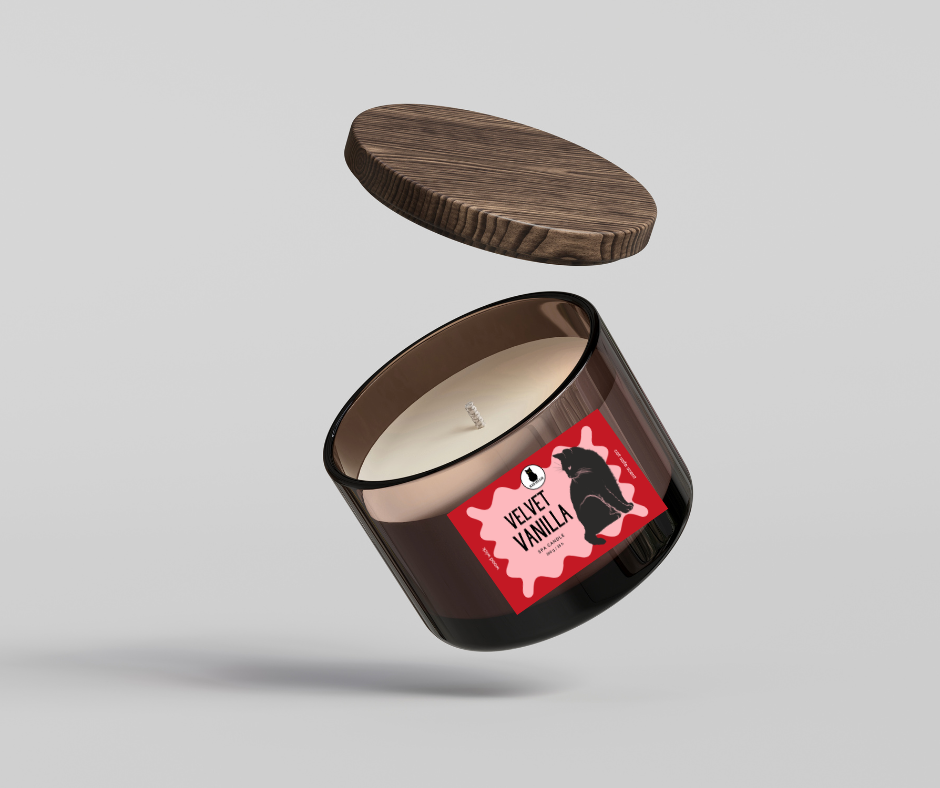 Black Cat looking over his shoulder at the label of a Candle with wooden lid on a light gray background