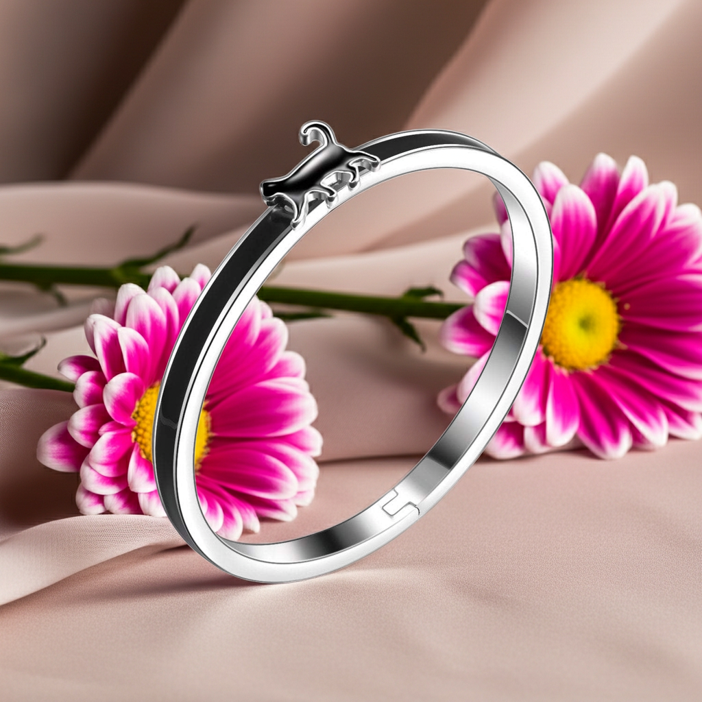 Silver bracelet with black enamel accents and a cat with pink flowers in the background