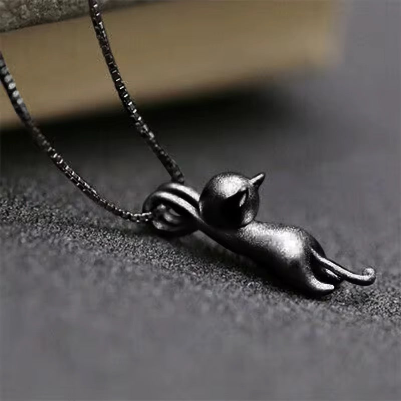 Tiny black cat pendant holds onto the black metal necklace with its front paws