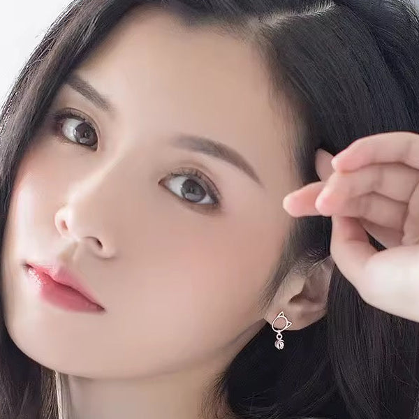 Woman with dark hair wearing petite cat earrings with dangling bell