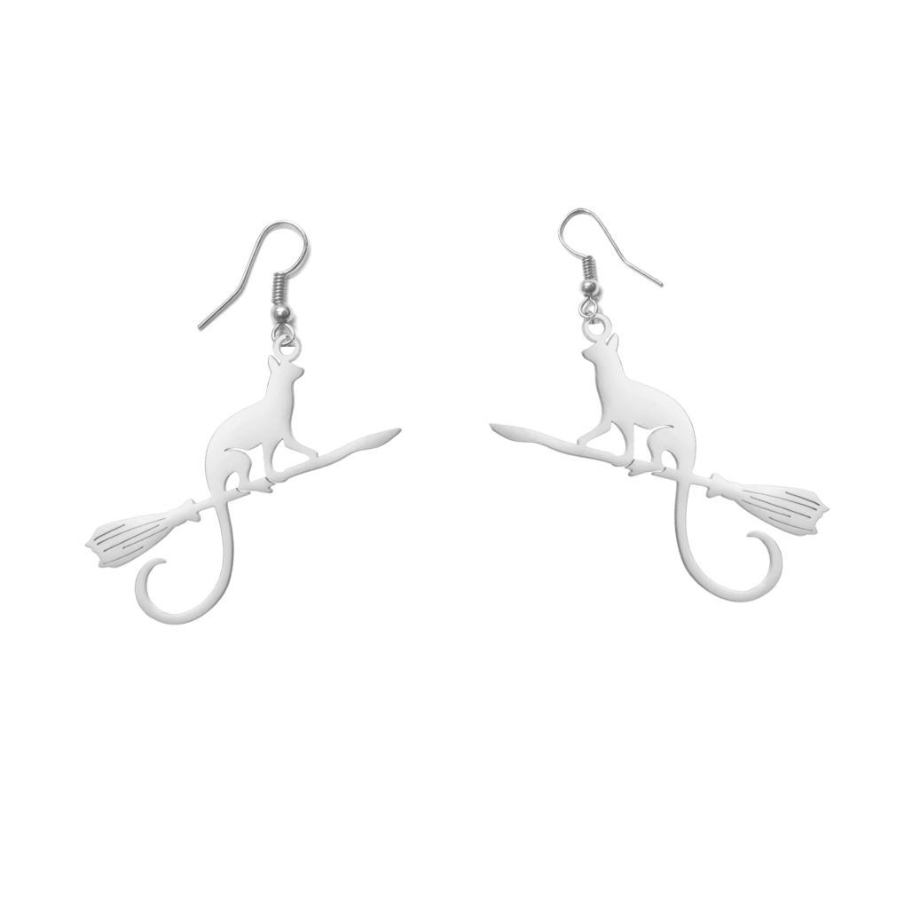 A pair of silver-toned dangle earrings featuring a silhouette of a cat sitting on a broomstick, shown against a plain white background.
