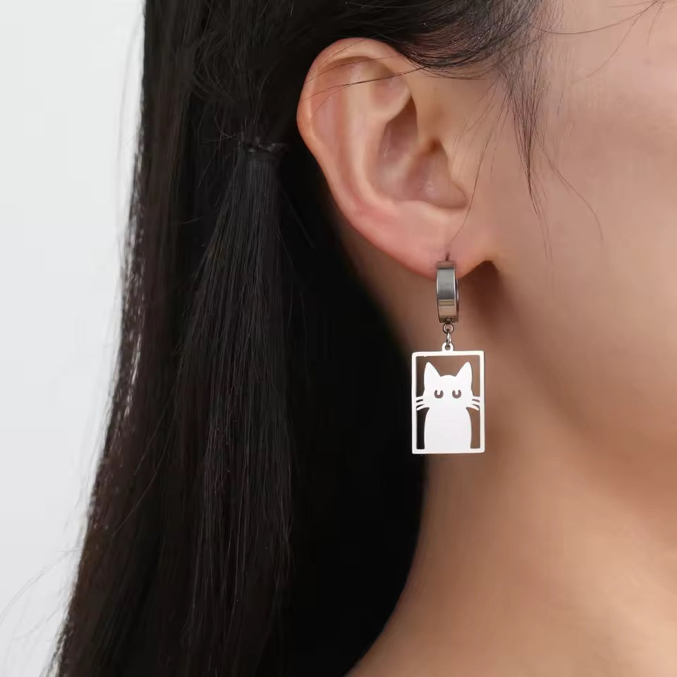 Silver hoop earrings feature a flat stainless cutout of a Cat in a Box on a person with dark hair