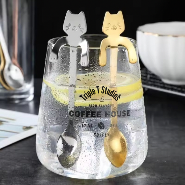 Clear glass with cat-shaped spoons and 'Triple T Studios Coffee House' branding.