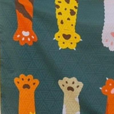 Closeup of a pattern of colorful cat paw prints on a teal background on a microfiber swimming pool towel