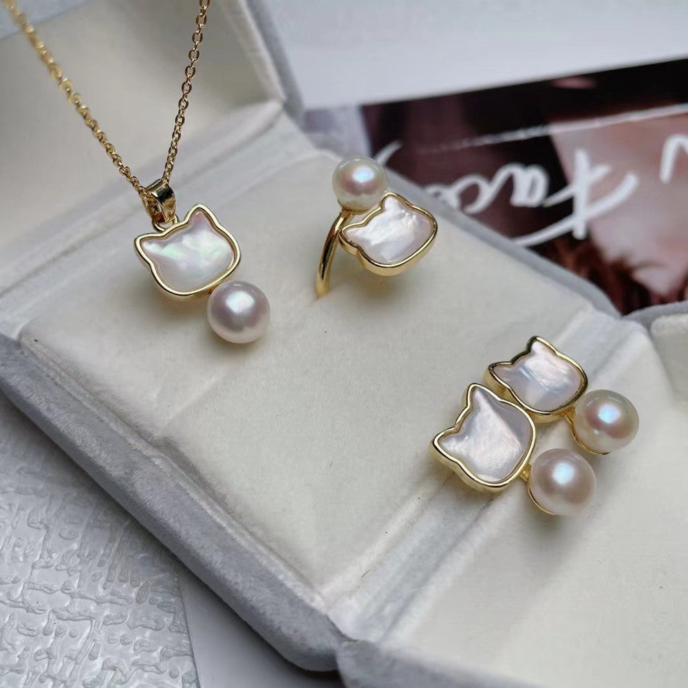 Cat shaped Pearl necklace and earrings with gold accents on a textured surface