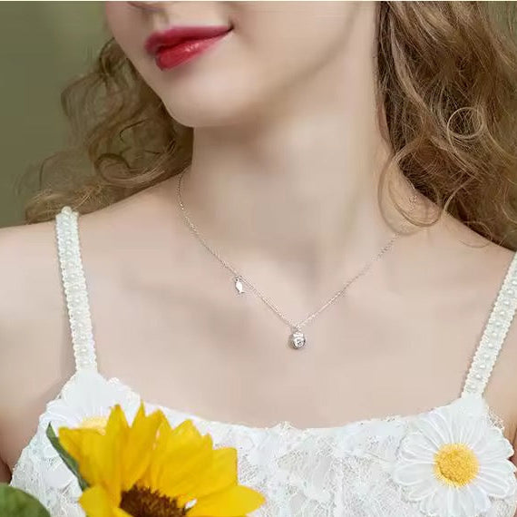 Woman wearing a delicate necklace with a sunflower and daisy design in the foreground.