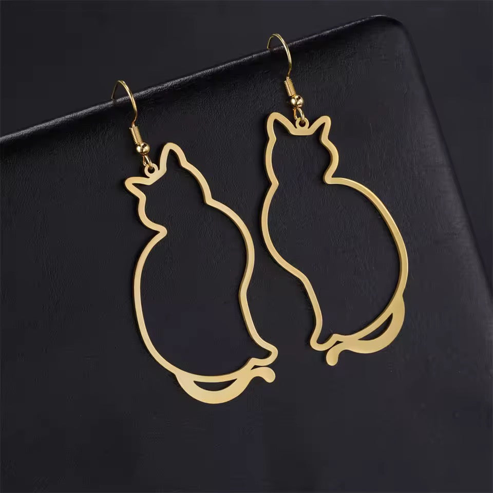 Gold cat-shaped earrings on a black background