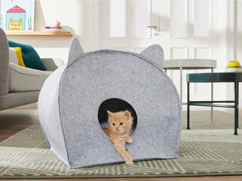 Gray cat-shaped pet house with a kitten peeking out in a living room.