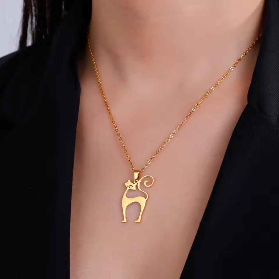 Gold necklace with a cat pendant on a person wearing a black outfit.