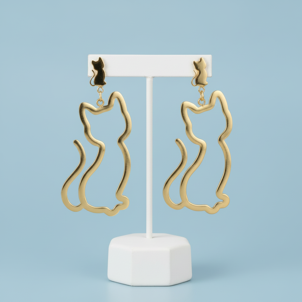 Gold cat-shaped earrings on a white stand against a light blue background