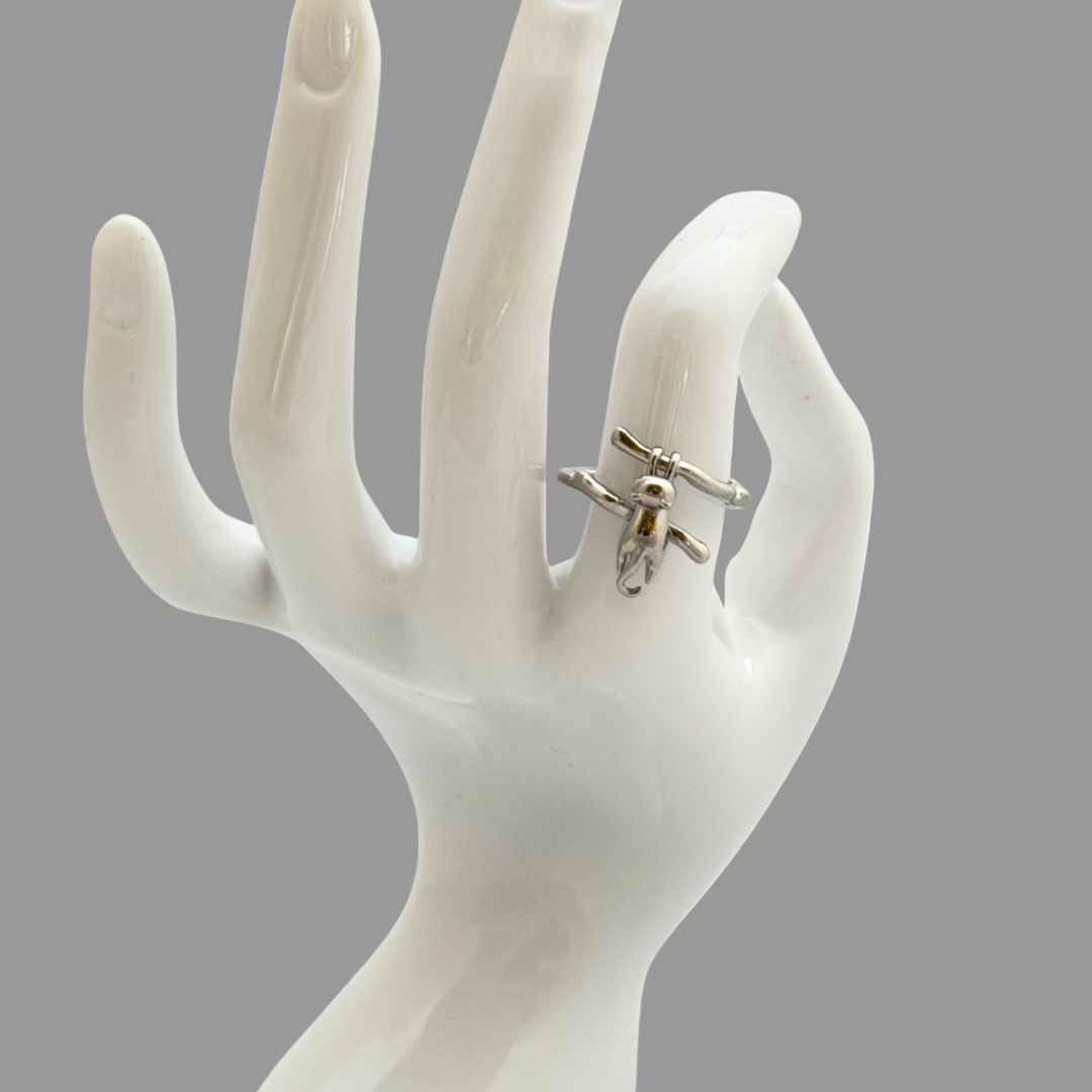 Silver ring on a white ceramic hand model against a gray background