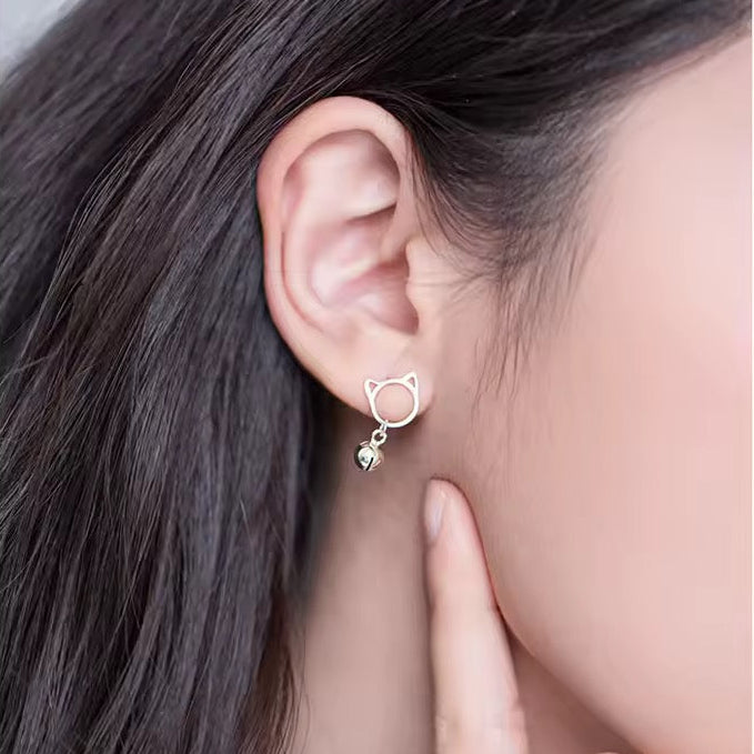Cat-shaped earring worn by a person with dark hair.