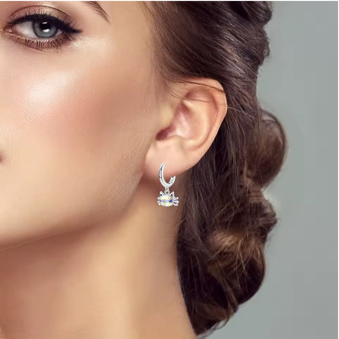 Close-up of a woman wearing a silver Cat Head earring with a blue gemstone on a neutral background