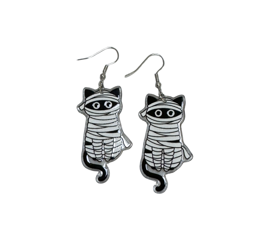 Pair of cat-shaped earrings with mummy design on a white background