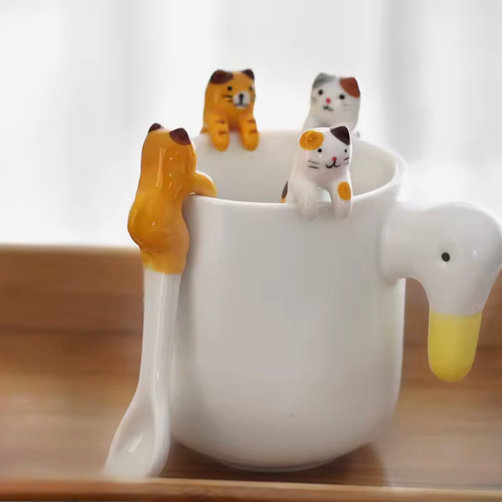 White swan mug with cat-shaped handles on a wooden surface