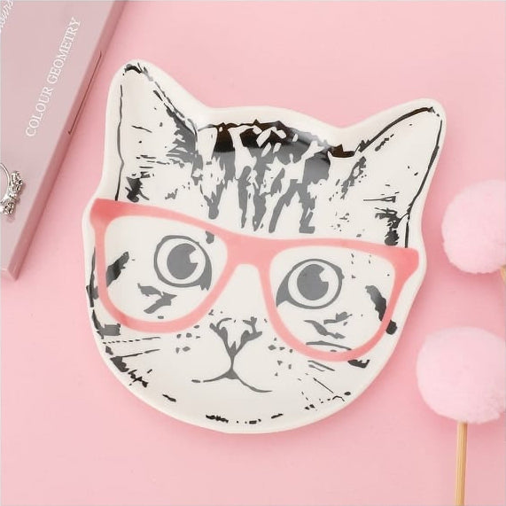 Cat-shaped ceramic trinket plate to hold jewelry or keys sits on a pink background