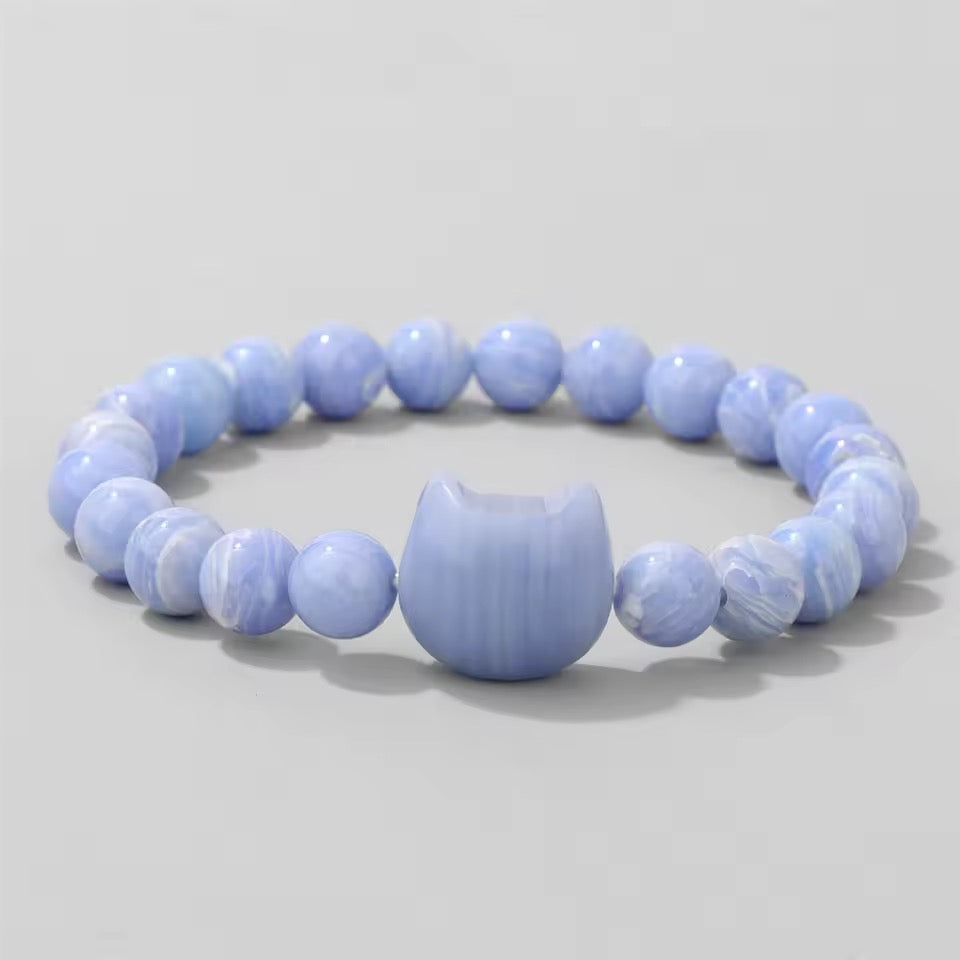 Purple agate beaded bracelet with a Cat Head accent bead carved from natural stone on a light gray background