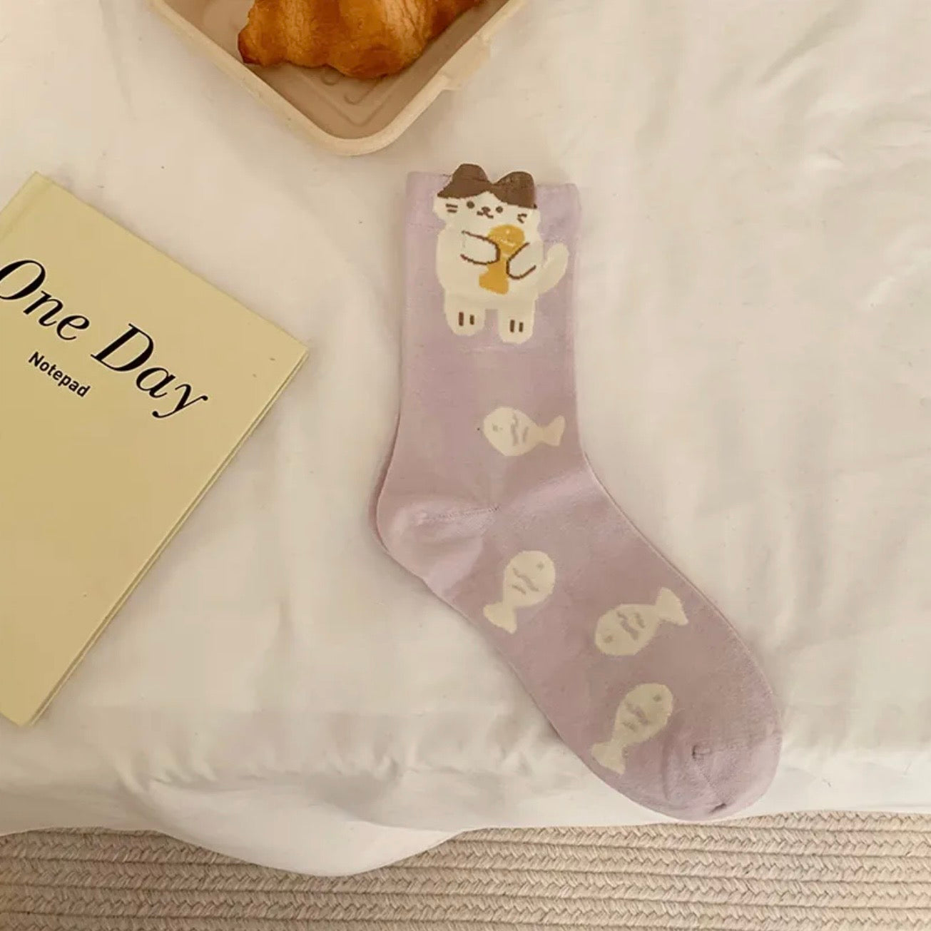 Purple sock with cartoon character on a white surface next to a yellow notepad