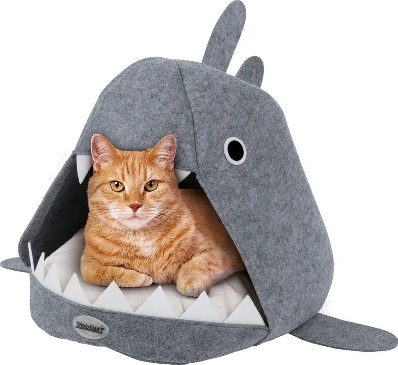 Cat lying inside a shark-shaped pet bed on a white background