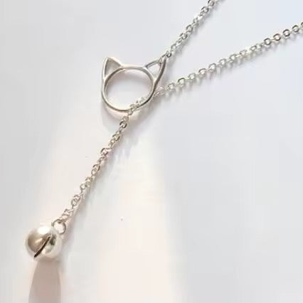 Silver plated lariat necklace with a cat bell that dangles through a cat-shaped pendant on a light background