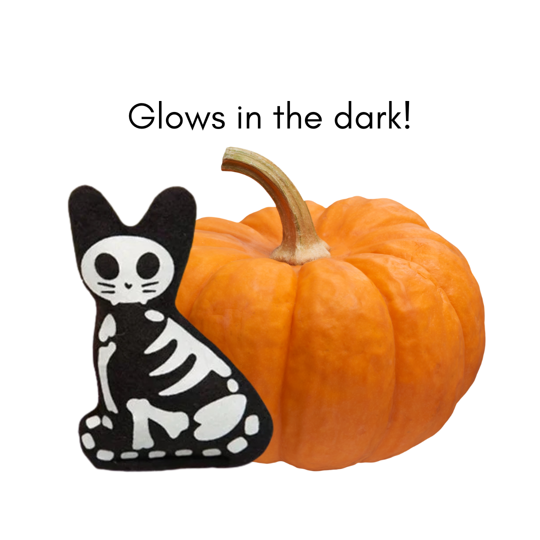 Black skeleton cat toy next to a pumpkin with text 'Glows in the dark!'.