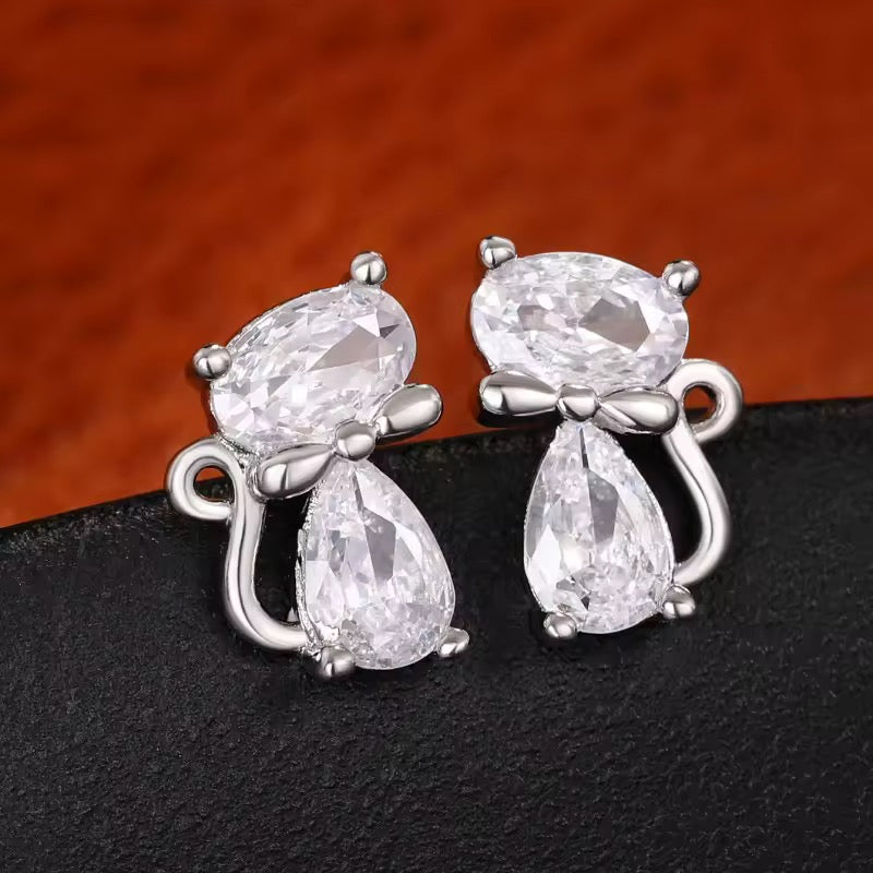 Clear Crystal Cats with silver bow ties and curly tail on a dark surface.