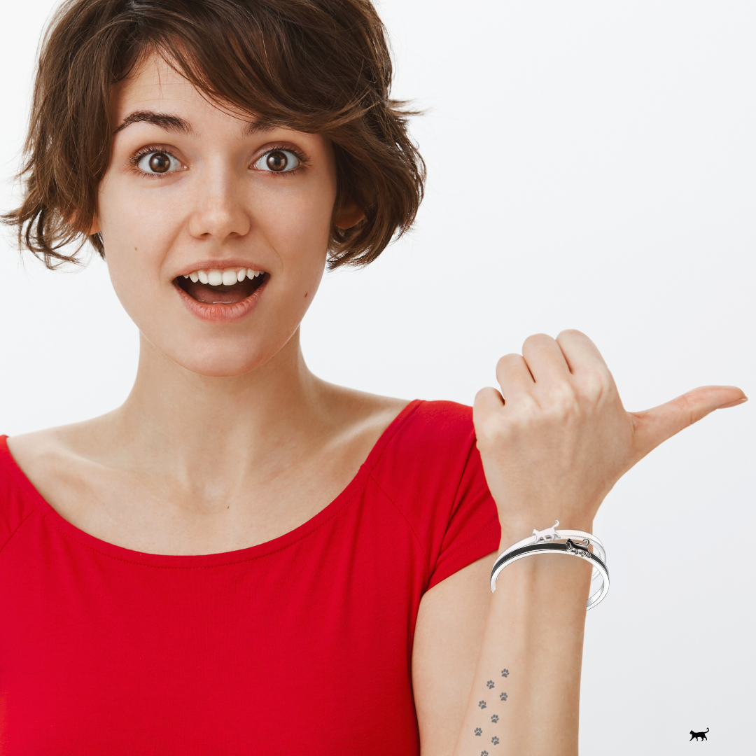 Woman in a red top gesturing with two Cat Bangle Bracelets on her wrist against a white background