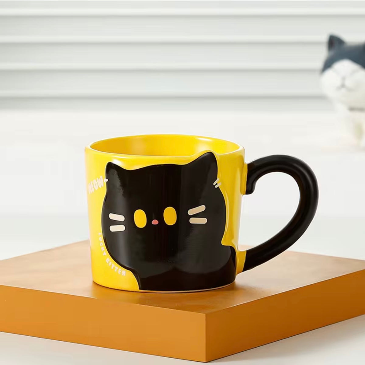 Yellow mug with black cat design on a wooden surface
