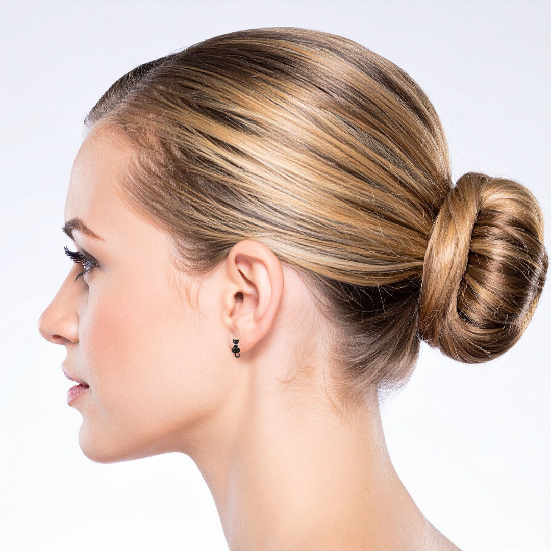 Side profile of a woman with blonde hair wearing rhinestone sparkly black cat earrings against a light background