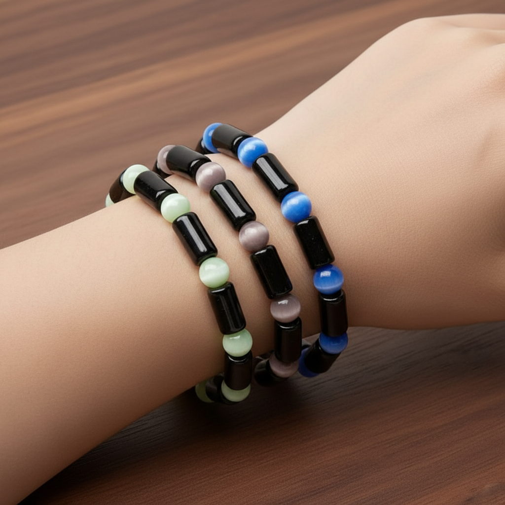 Purple, green, and blue glass beaded Cats Eye bracelets on a wrist against a wooden background