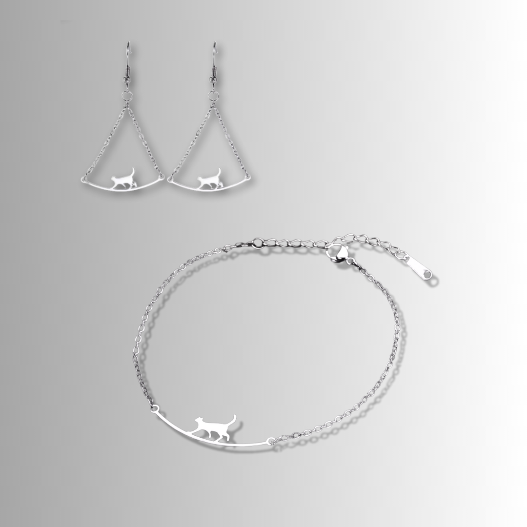 Silver earrings and bracelet with cat designs on a gray background