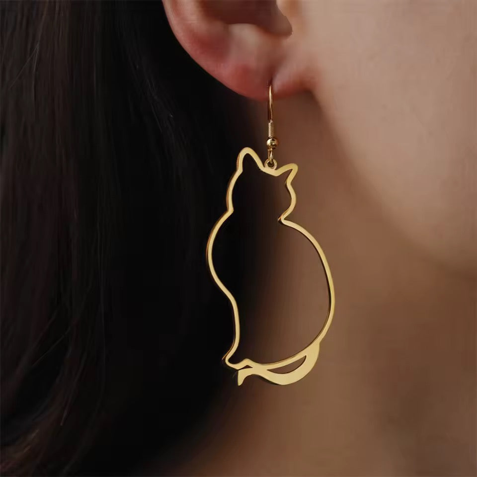 Gold Triple T Studios Fat Cat gold earrings worn by a person with dark hair