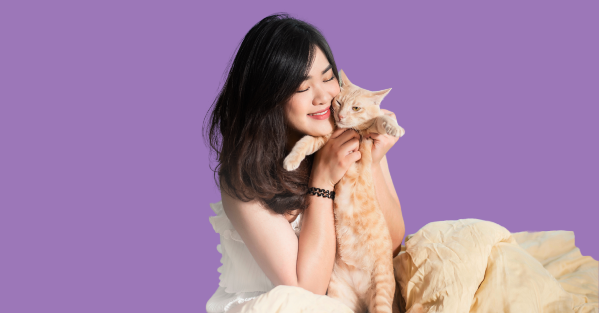 Woman holding a cat against a purple background