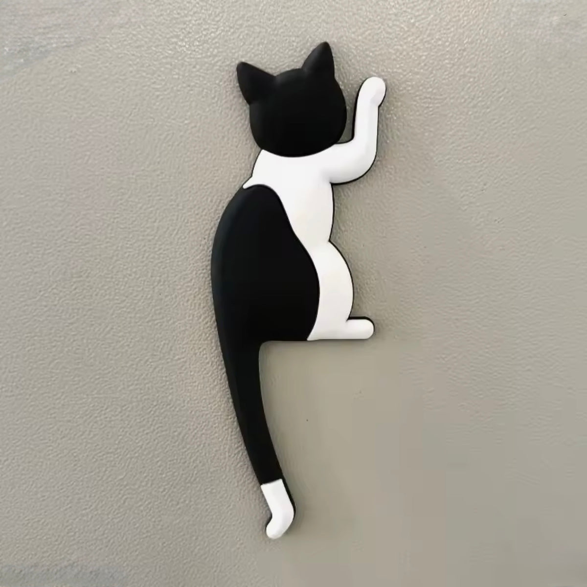 Black and white cat-shaped magnet hook on a gray wall
