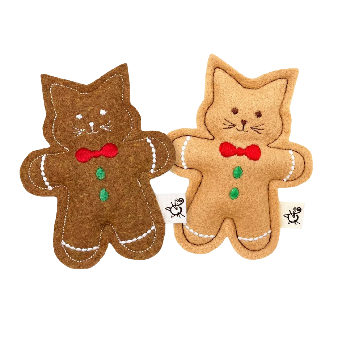 Two gingerbread cat-shaped toys with red bows on a white background
